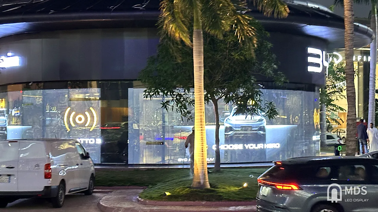 BYD Jeddah showroom at night from the street, transparent LED facade playing a model campaign