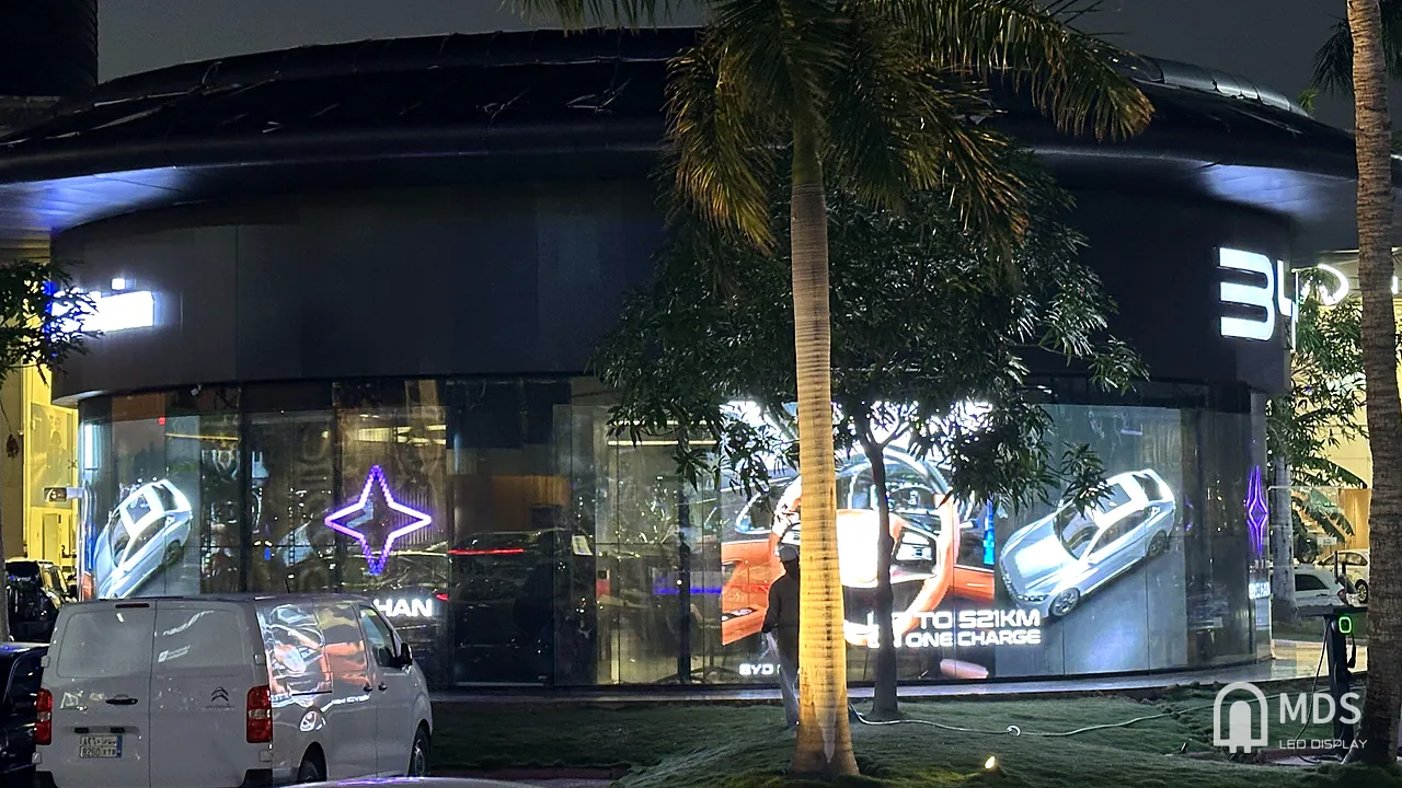 BYD Jeddah showroom at night: double-sided transparent LED playing a range campaign on the street-facing glass